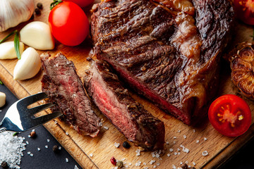 Fresh juicy ribeye steak with a set of spices on a cutting board