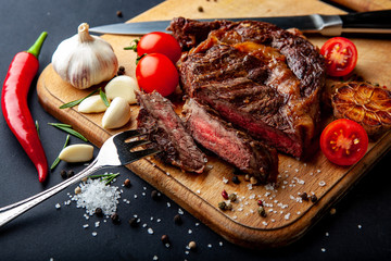 Fresh juicy ribeye steak with a set of spices on a cutting board