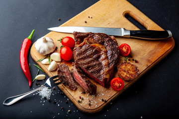 Fresh juicy ribeye steak with a set of spices on a cutting board