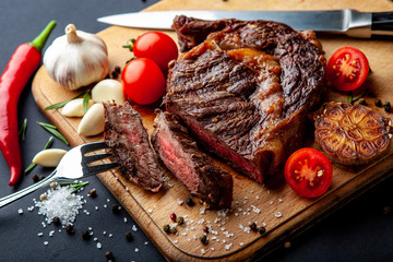 Fresh juicy ribeye steak with a set of spices on a cutting board