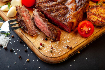 Fresh juicy ribeye steak with a set of spices on a cutting board