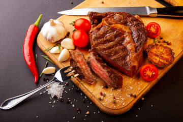 Fresh juicy ribeye steak with a set of spices on a cutting board