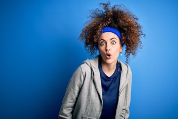 Fototapeta na wymiar Young beautiful sportswoman with curly hair and piercing standing wearing sportswear afraid and shocked with surprise expression, fear and excited face.
