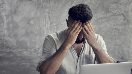 A man suffering headache from laptop work a painful head pain and looking overworked, worried and...