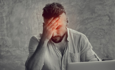 A man suffering headache from a laptop work. Painful head pain and looking overworked and...