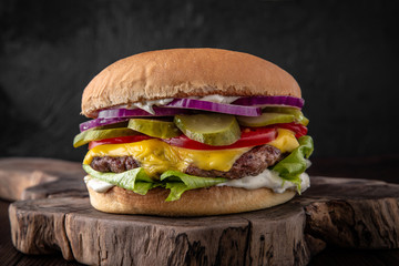 Delicious juicy cheeseburger from Brioche Bun, Aged beef cutlet, American Cheddar, Tomatoes, Gherkins, Red onions, Iceberg. Hamburger for poster or menu.