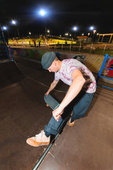 A young skatecrack in a night skatepark does a halfpipe jump jump. Youth Culture Leisure Concept at Night