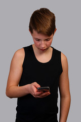 Portrait of a teenager in a tank top on a gray background with a phone.