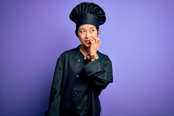 Young beautiful chinese chef woman wearing cooker uniform and hat over purple background looking stressed and nervous with hands on mouth biting nails. Anxiety problem.