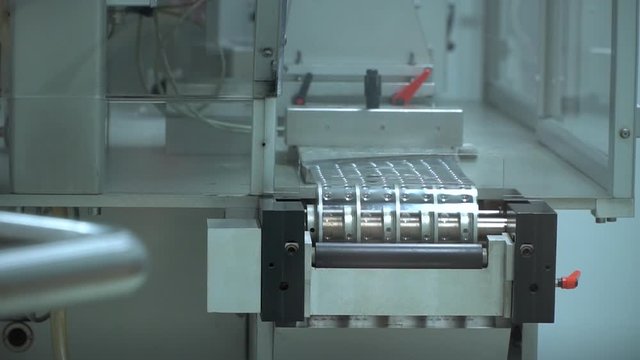 Shiny dimpled plastic ream circles around medical conveyor belt, static
