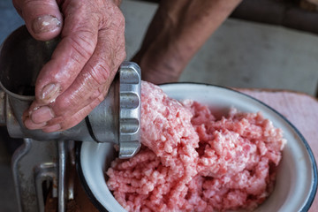Rough hands of old man make mincemeat of vintage meat grinder. Close up
