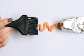 Squeezed out tubes of hair dye and brush on a white background