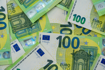Banknotes of 100 hundred euros are scattered in a chaotic manner. European currency lies on the table. Close-up. Blank for design, background. View from above.