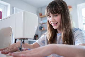 Young Girl Learning How To Use Sewing Machine At Home