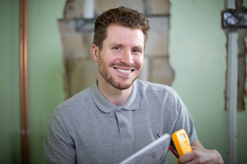 Portrait Of Electrician Inside House Being Renovated Studying Plans