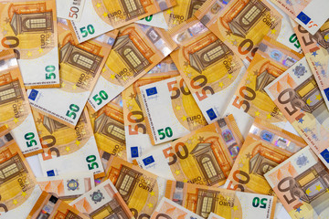 Banknotes of 50 fifty euros are scattered in a chaotic manner. European currency blank for design, background. View from above.