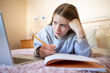 Stressed Female Teenager Having Problems Using Laptop For Homework Or Home Schooling