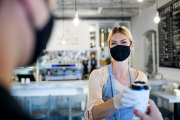Woman with face mask serving customer, shop open after lockdown quarantine.