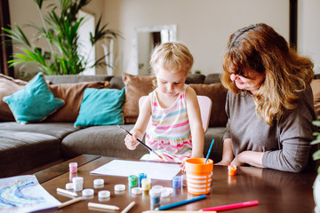 Naklejka premium Grandmother and granddaughter drawing together with watercolors at home. Little girl has a lesson with her drawing teacher.