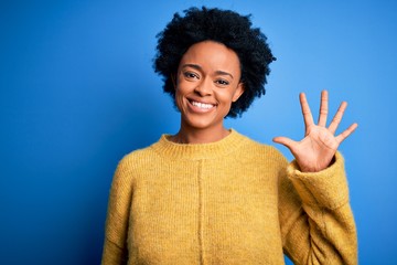 Young beautiful African American afro woman with curly hair wearing yellow casual sweater showing...