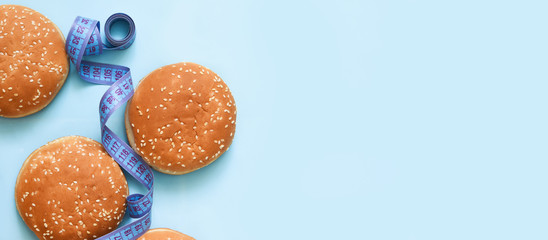 Fototapeta na wymiar Hamburger bun and centimeter on a blue background. Fast food. Diet. Fitness.