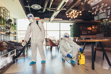 Professional workers in hazmat suits disinfecting indoor of cafe or restaurant, pandemic health risk, coronavirus - obrazy, fototapety, plakaty