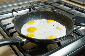 Six eggs in close-up frying in a pan on a gas stove