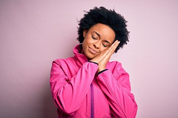 Fototapeta na wymiar Young African American afro sportswoman with curly hair wearing sportswear doin sport sleeping tired dreaming and posing with hands together while smiling with closed eyes.