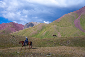 Fototapeta na wymiar Beautiful landscape of mountain peaks. Hilly area. Grazing donkey. Horse rider.