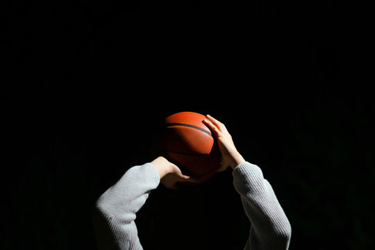 Close up of professional basketball player throwing a ball at night. Street basketball athlete training for competition in the dark