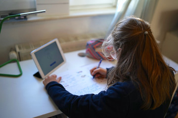Real 10 year old girl is doing homeschooling, learning at home, doing homework      