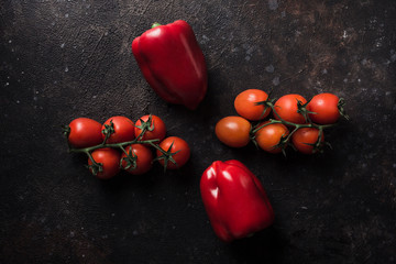 Fresh spring paprika and cherry tomatoes on a dark background. Top view with a copy space.