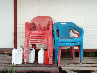 Fototapeta na wymiar Red and blue old plastic chair storage, White plastic jerry can in tropical environment. Caribbean culture