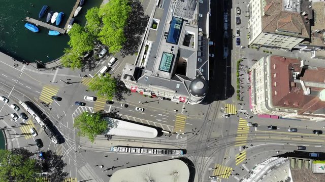 Zuerich Switzerland Drone Aerial Top View of Bellevue Tram Station with Tram Traffic - Slow Upwards Tilt Revealing Limmat River and Beautiful Old Town