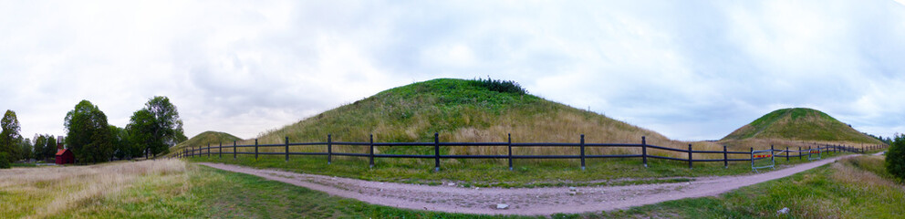 Fototapeta premium Panoramic view of Gamla Uppsala. The three large royal mounds. According to ancient mythology and folklore, the three gods Thor, Odin and Freyr. Sweden.