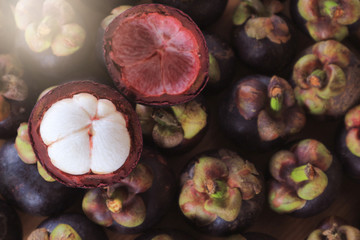 ripe mangosteen fruits and cross section showing the thick purple skin and white for background.