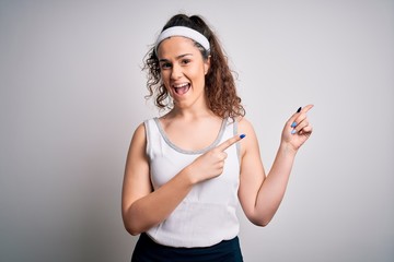 Beautiful sportswoman with curly hair wearing sportswear over isolated white background smiling and looking at the camera pointing with two hands and fingers to the side.