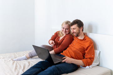 Smiling young adult couple using laptop and laughing together