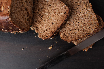 delicious fresh baked slices of bread with sunflower seeds on a dark table, horizontal image