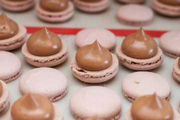 Making chocolate macaroons. Filling shells with chocolate ganache. Selective focus.