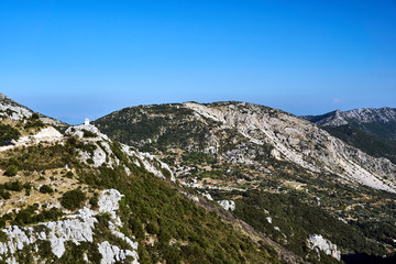 Mountain landscape with rocky peaks and the bell tower of the Orthodox chapel on the island of Lefkada.