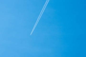 Airplane flying in the clear blue sky with white trail along the route
