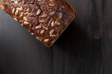 delicious fresh baked bread with bran sunflower seeds on a dark table, horizontal image