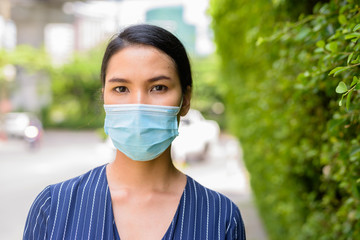 Face of young Asian businesswoman with mask for protection from corona virus outbreak in the streets outdoors