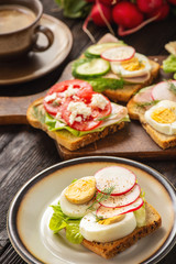 Toasts with eggs, cheese, ham, radish, cucumbers and tomatoes , breakfast idea.