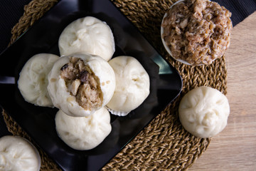White buns on a black plate on a brown wooden floor.