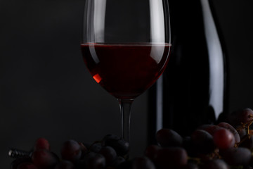 The red wine in the glass, along with a bottle of wine made from red grapes, is laid on a wooden floor and a beautiful backdrop. Ready for partying