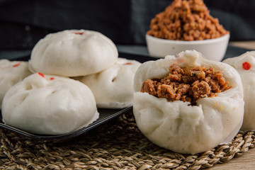 White buns on a black plate on a brown wooden floor.