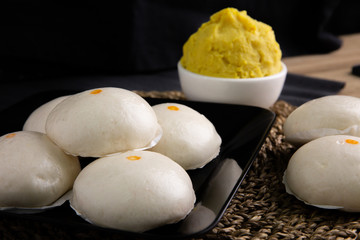 White buns on a black plate on a brown wooden floor.