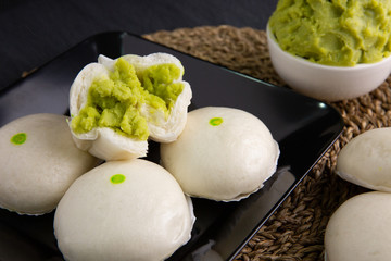 White buns on a black plate on a brown wooden floor.